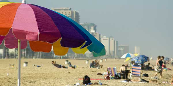 Beachgoers relax on the sand with colorful umbrellas.