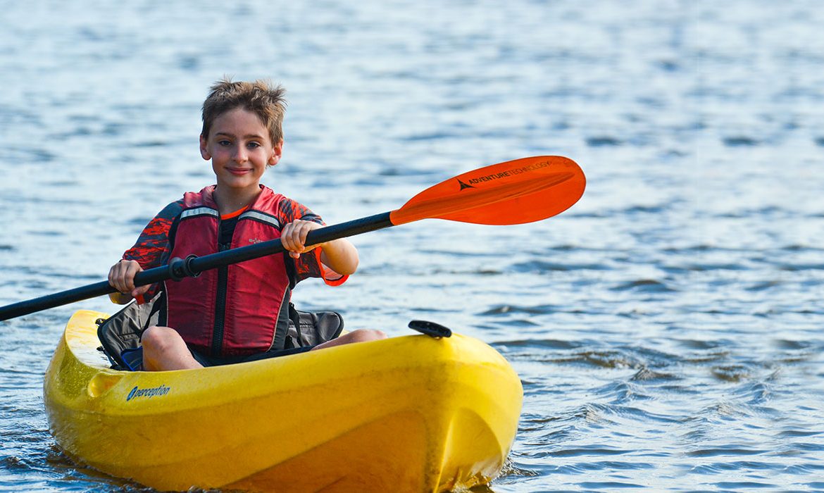 Young boy wearing life jacket smiling on kayak in Oklahoma City