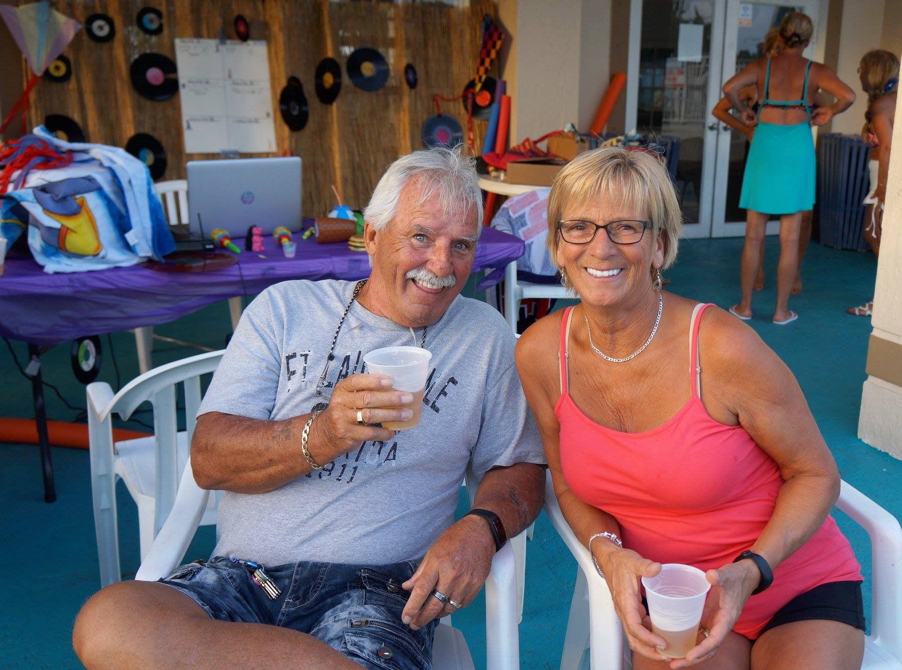 A senior couple drink beer from plastic cups at a resort.