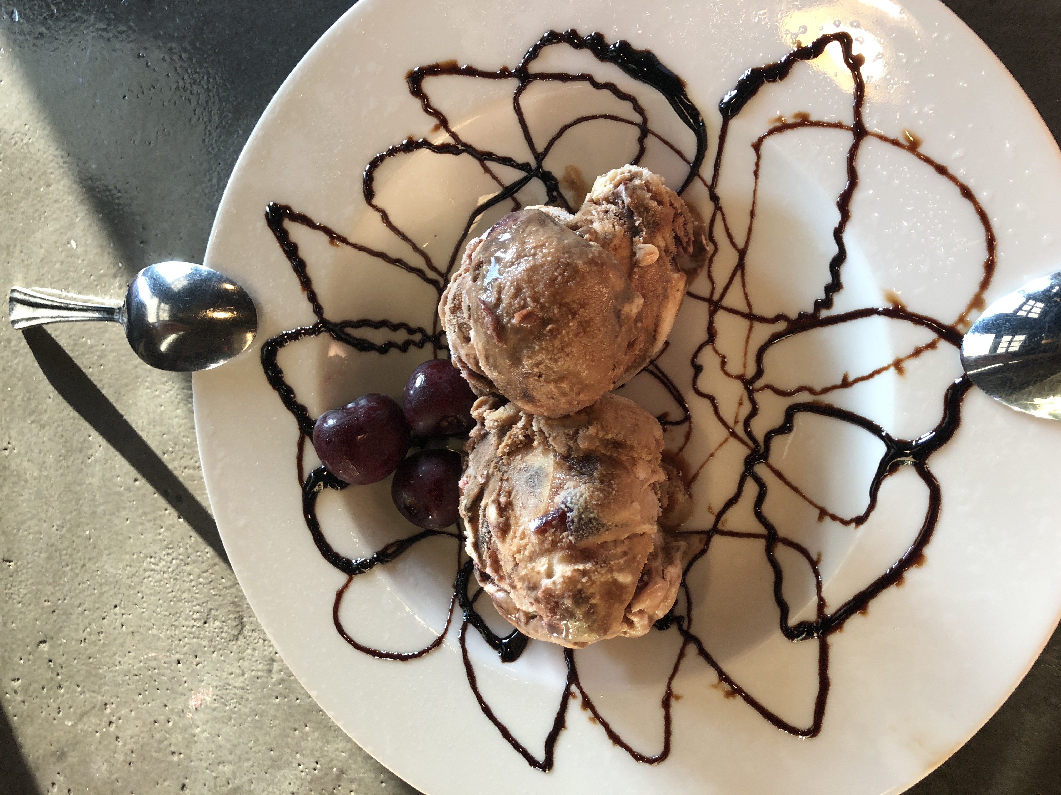 Two scoops of ice cream surrounded by curls of chocolate sauce on the plate.