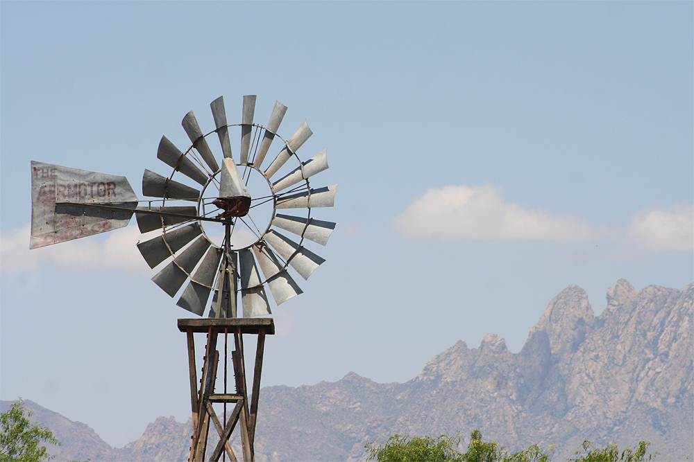 Metal windmill in stark desert landscape.