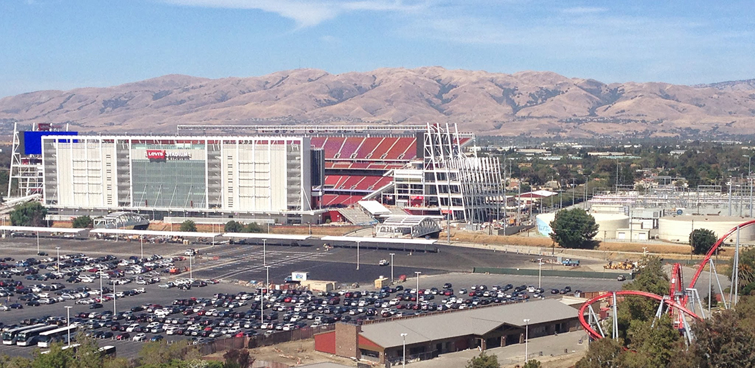 Football stadium with rolling hills in the background.