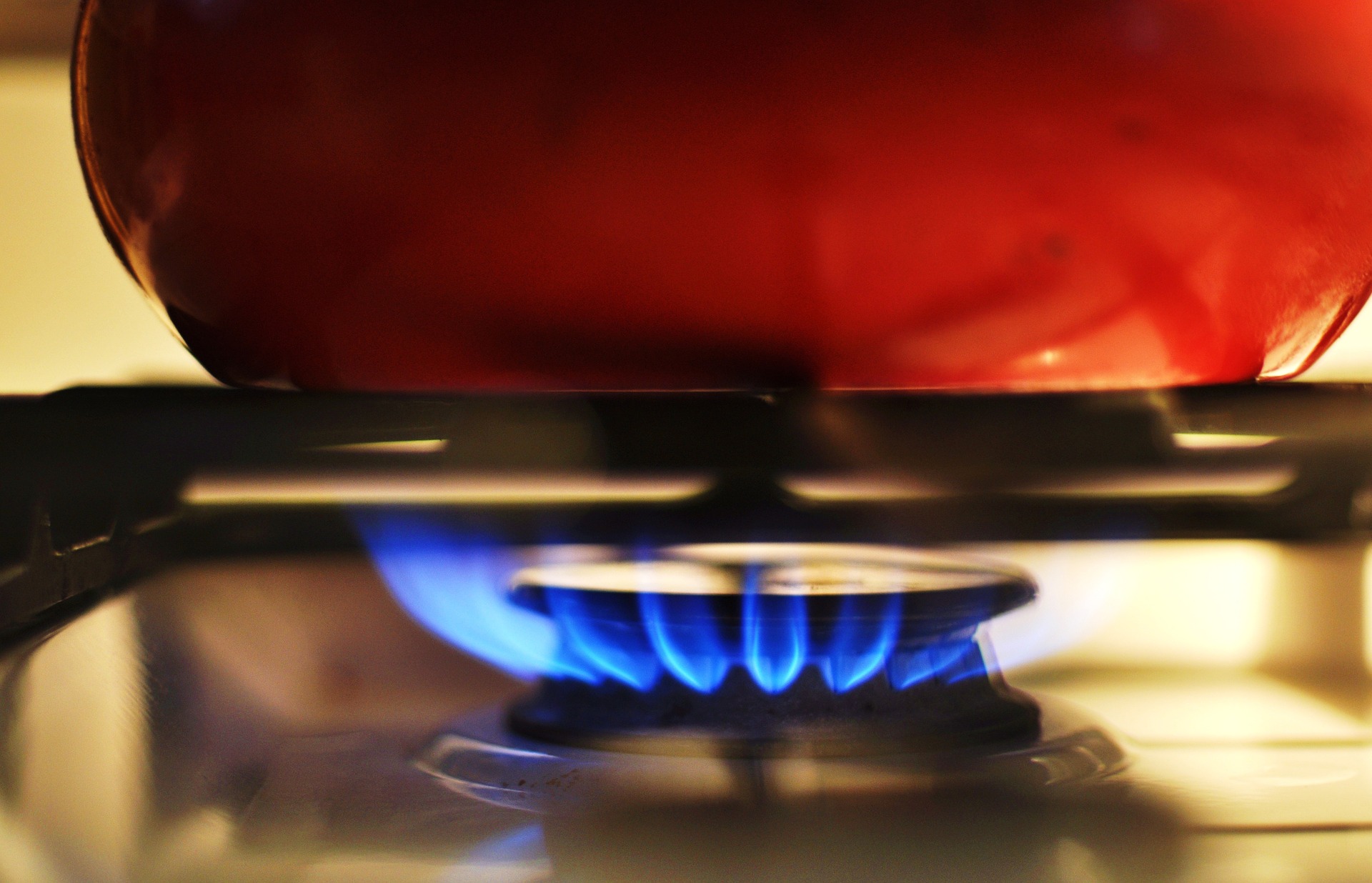 A red kettle sits on a burner with flames.