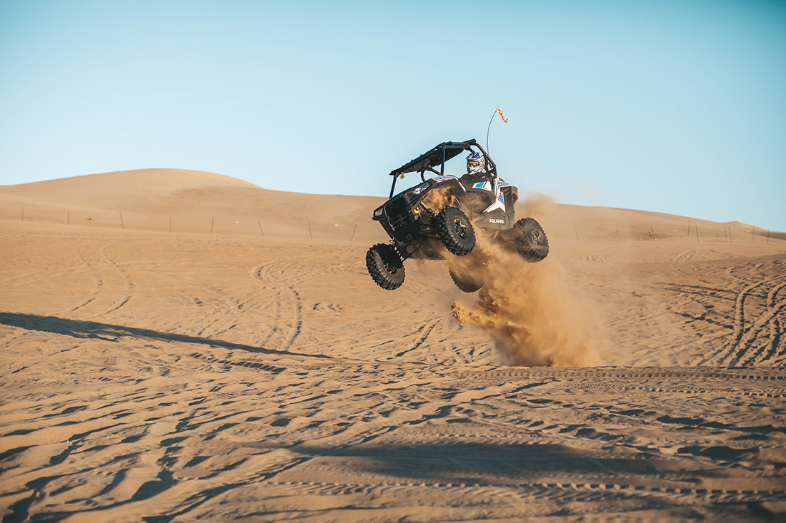 An offroad vehicle gets air in the dunes around Pismo
