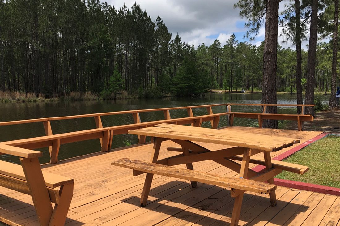Sunroamers RV Resort is now rated — A picnic table on a patio overlooking a lake.