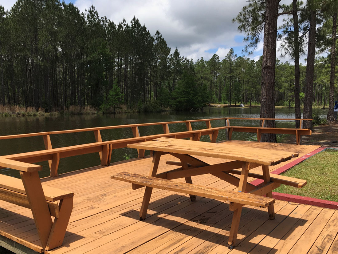 Sunroamers RV Resort is now rated — A picnic table on a patio overlooking a lake.