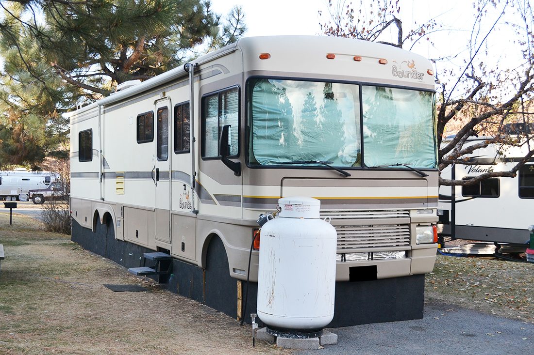 An RV parked at a sit with skirt protecting wheels.