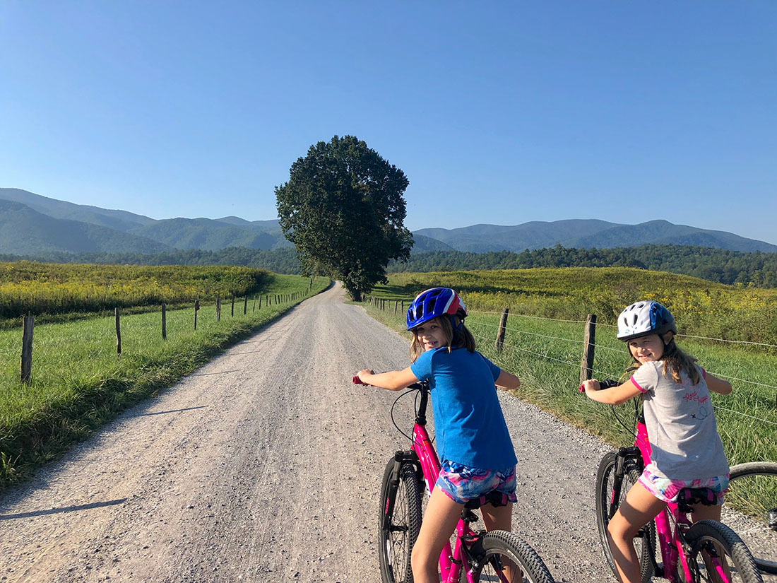 Two girls on biks about to set out on a dirt trail.