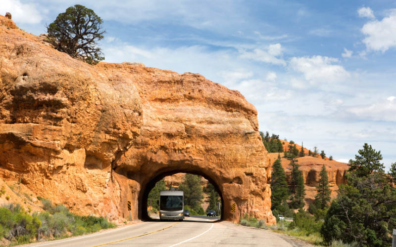 A motorhome goes under a rock arch.