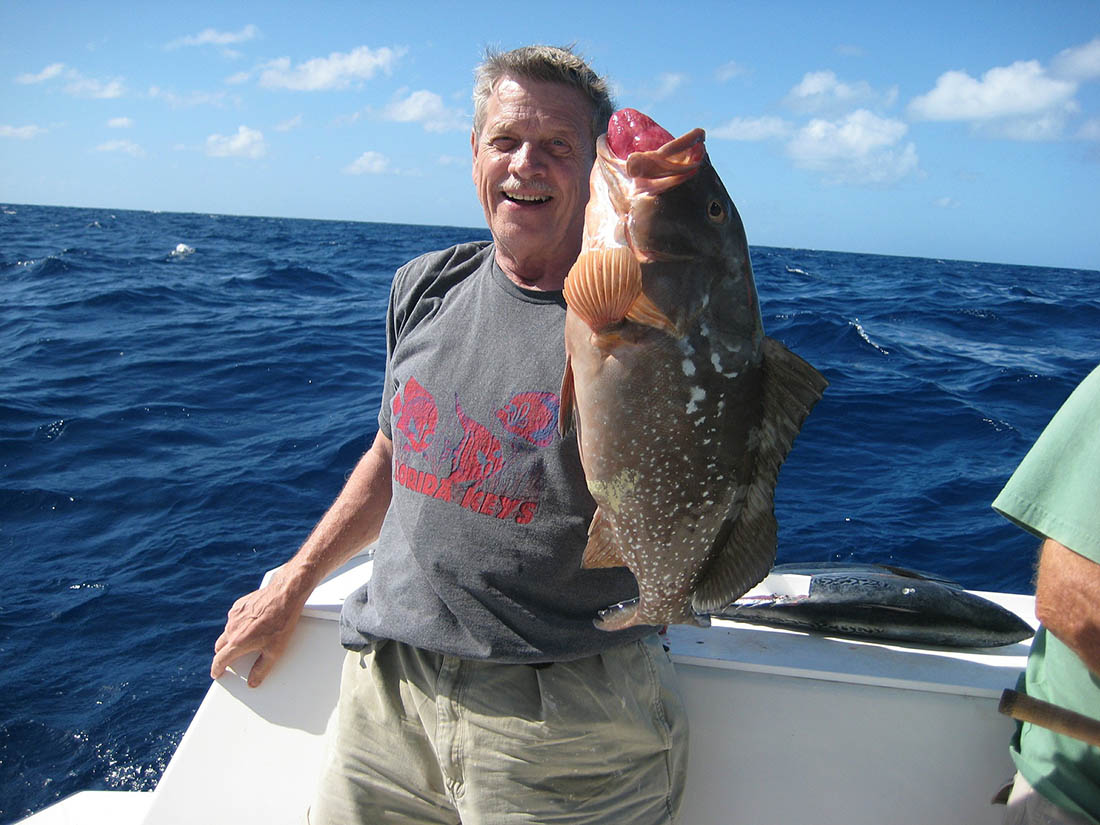 Man holding a grouper caught in the ocean.