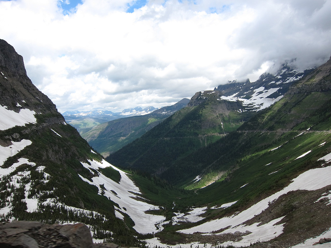 Glacier National Park Patches of snow in a green mountain valley.