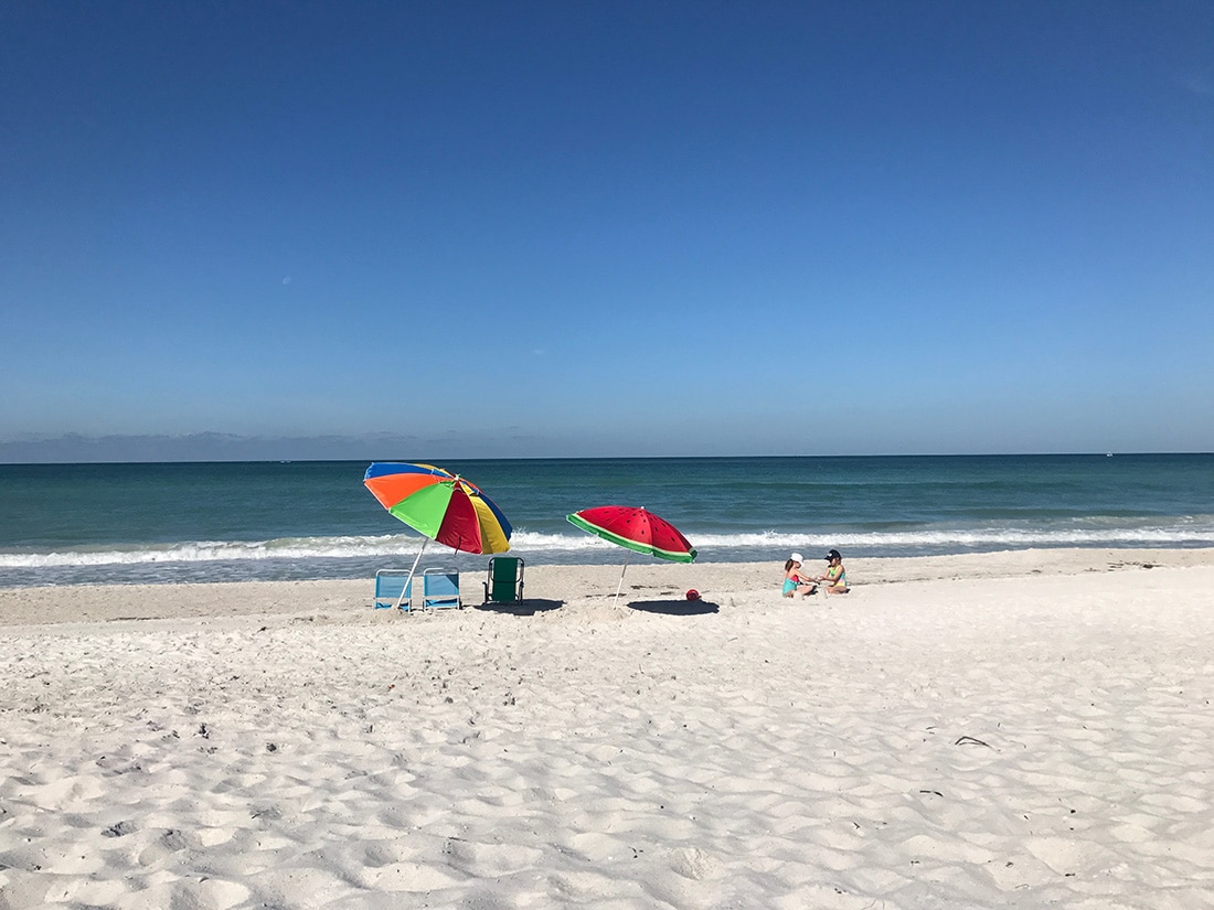 Two colorful umbrellas on a white-sand beach.