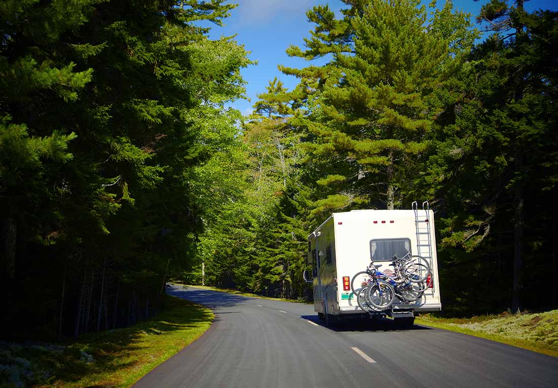 RV driving on a tree-lined road in Maine