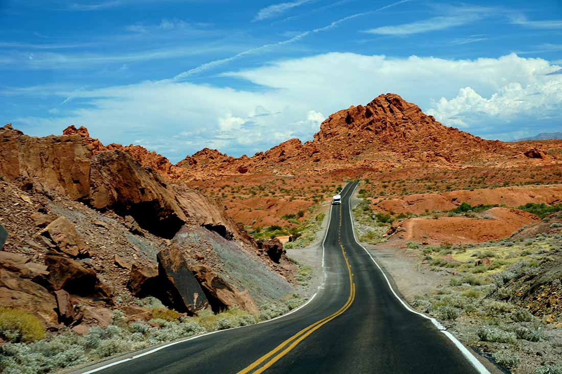 Valley of Fire — An RV traveling on a new section of paved highway in a very remote location during summer.