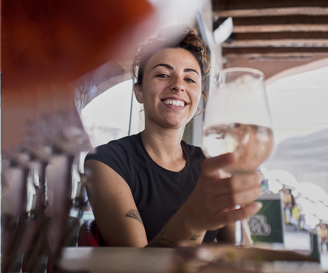 A woman smiles as she raises a wine glass