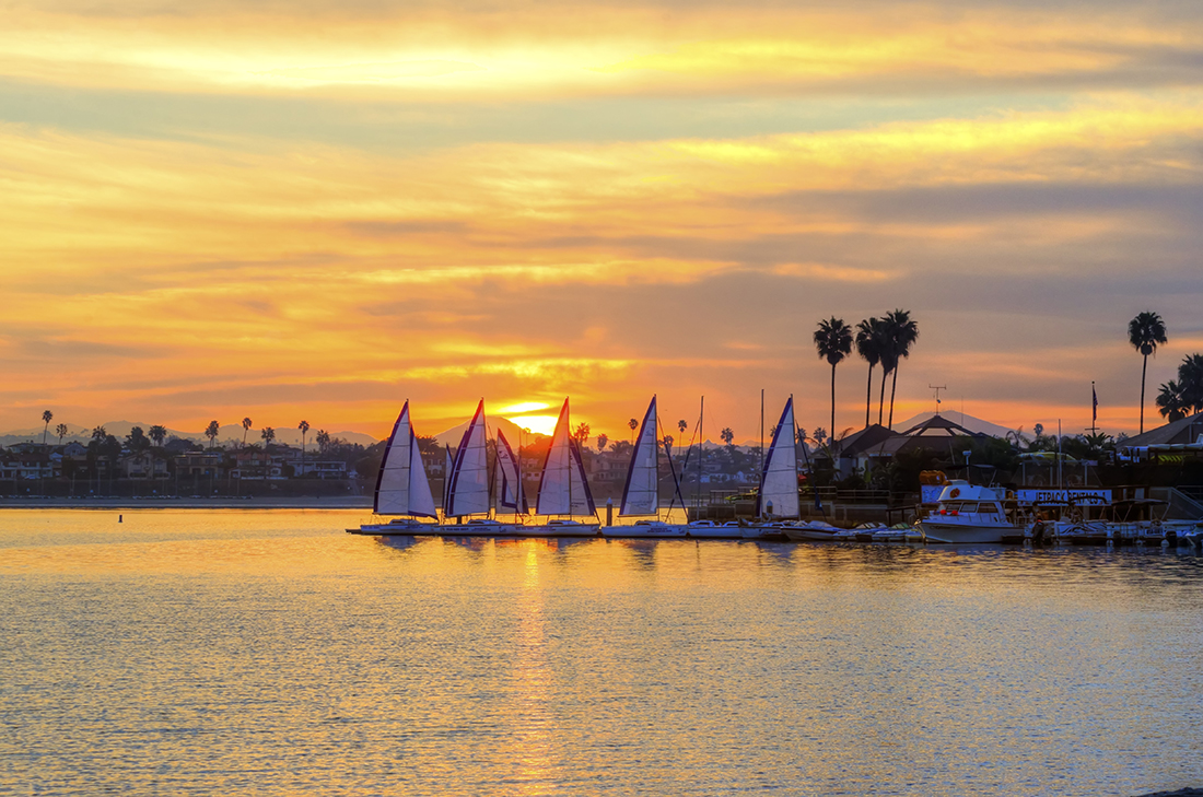 , California in the United States of America. A view of the palm trees, sail boats and beautiful saltwater bay at sunset.