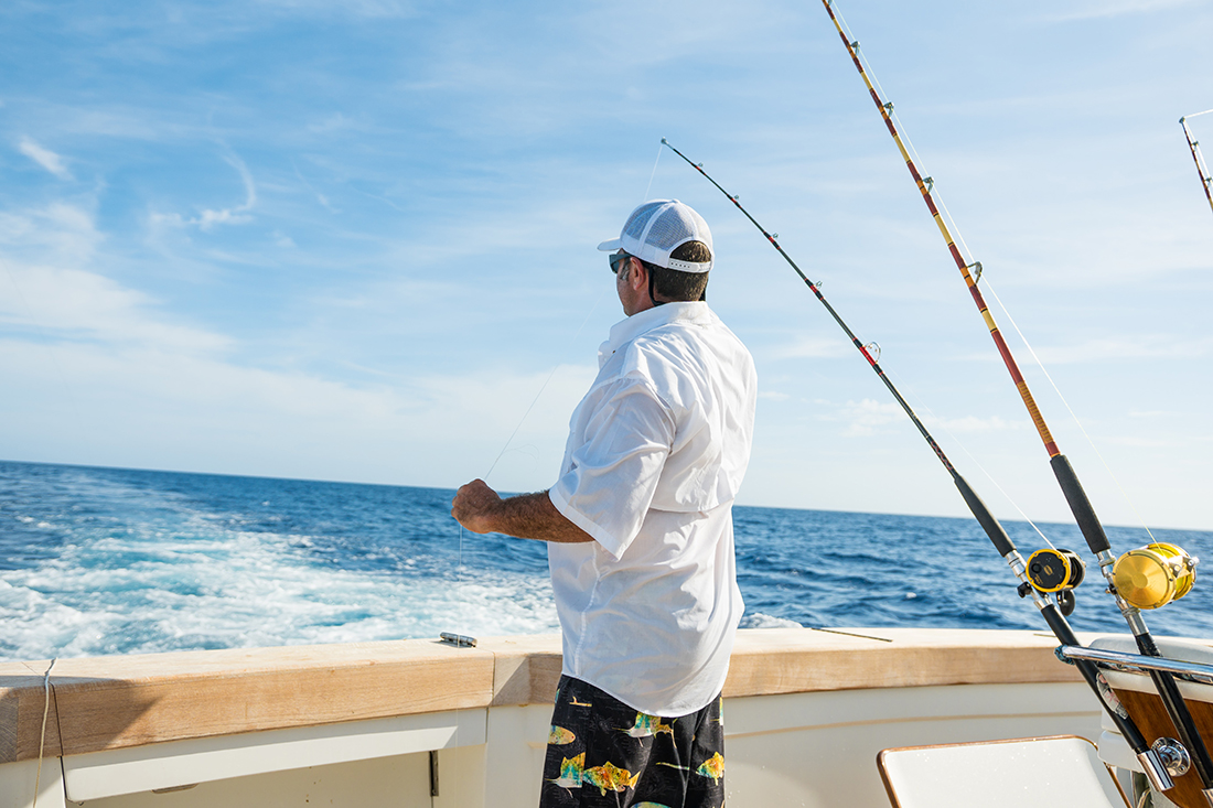 A man with fishing poles on a charter boat.