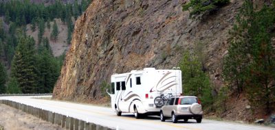 An RV driving along a road carved into a mountainside.
