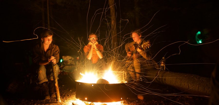 Three people gathered around a campfire.