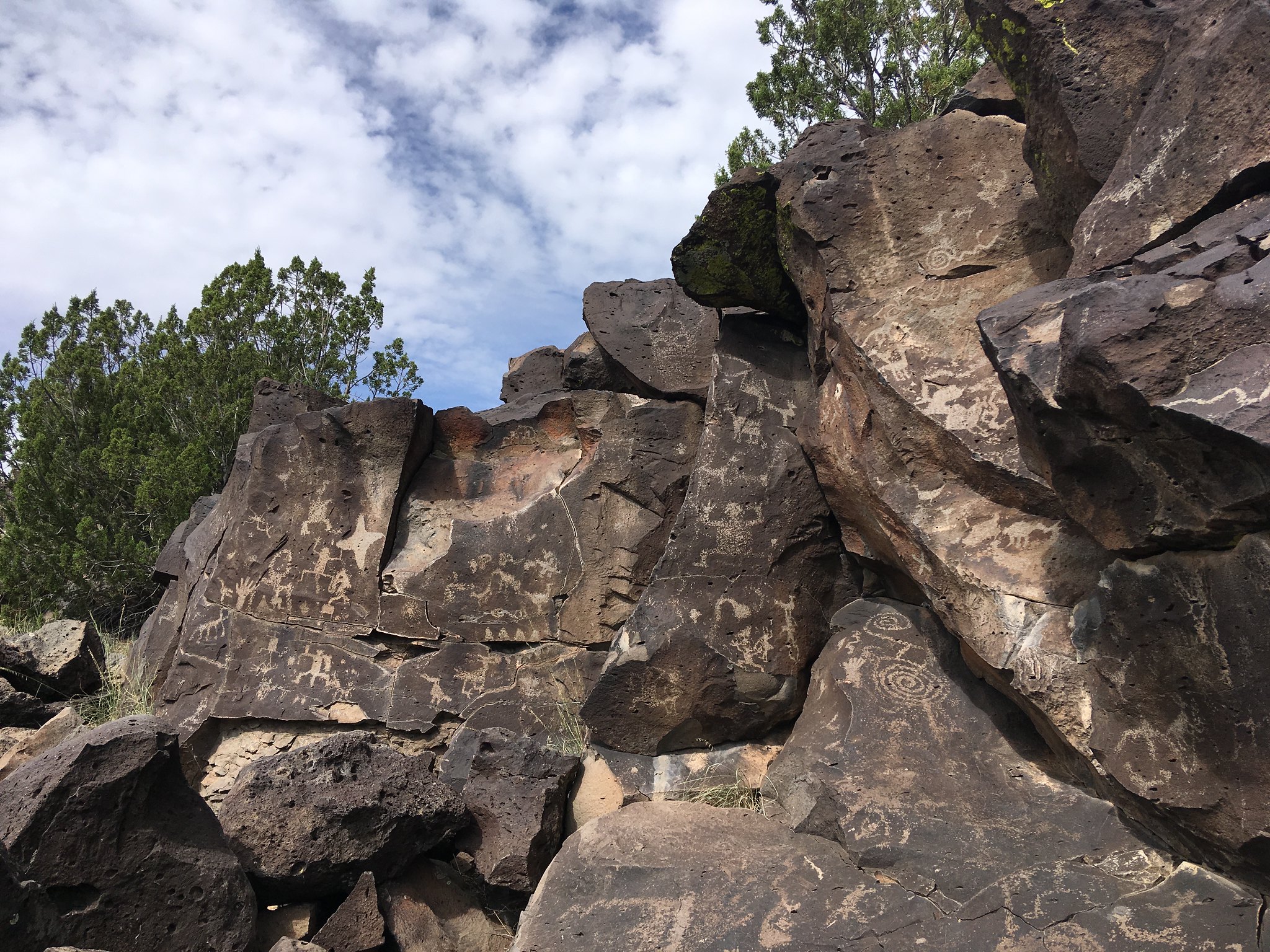 Santa Fe Petroglyphs Petroglyphs etched in dark-colored rock.