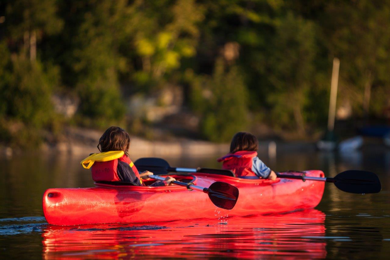 Two kids kayaking on a lake.