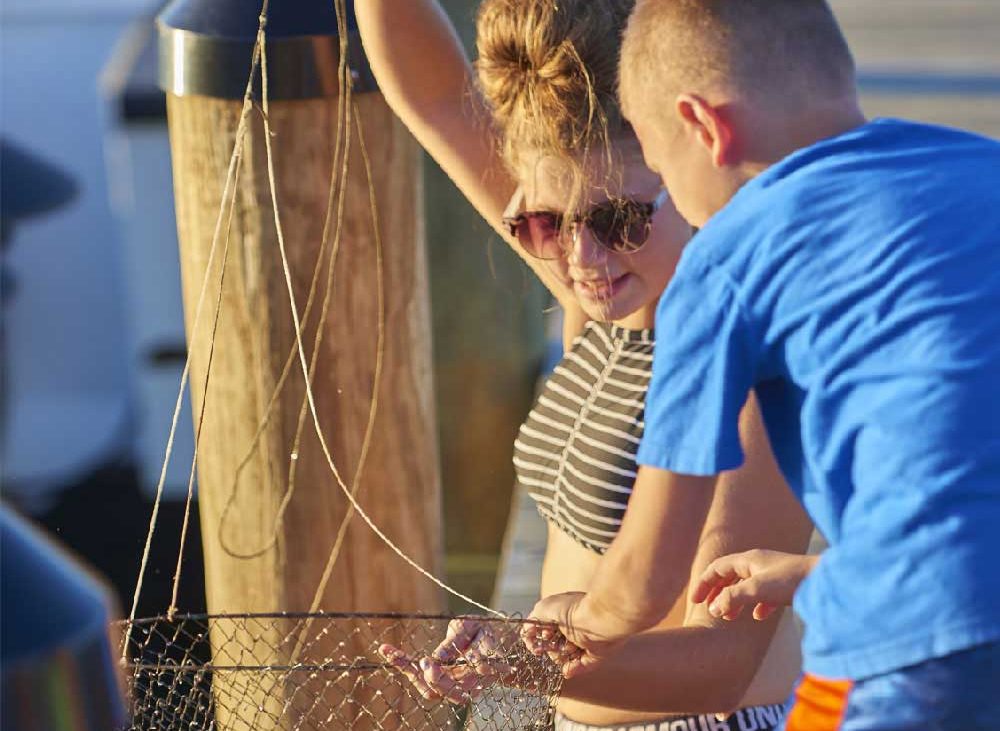 A teenager and child catch a crab in a net.