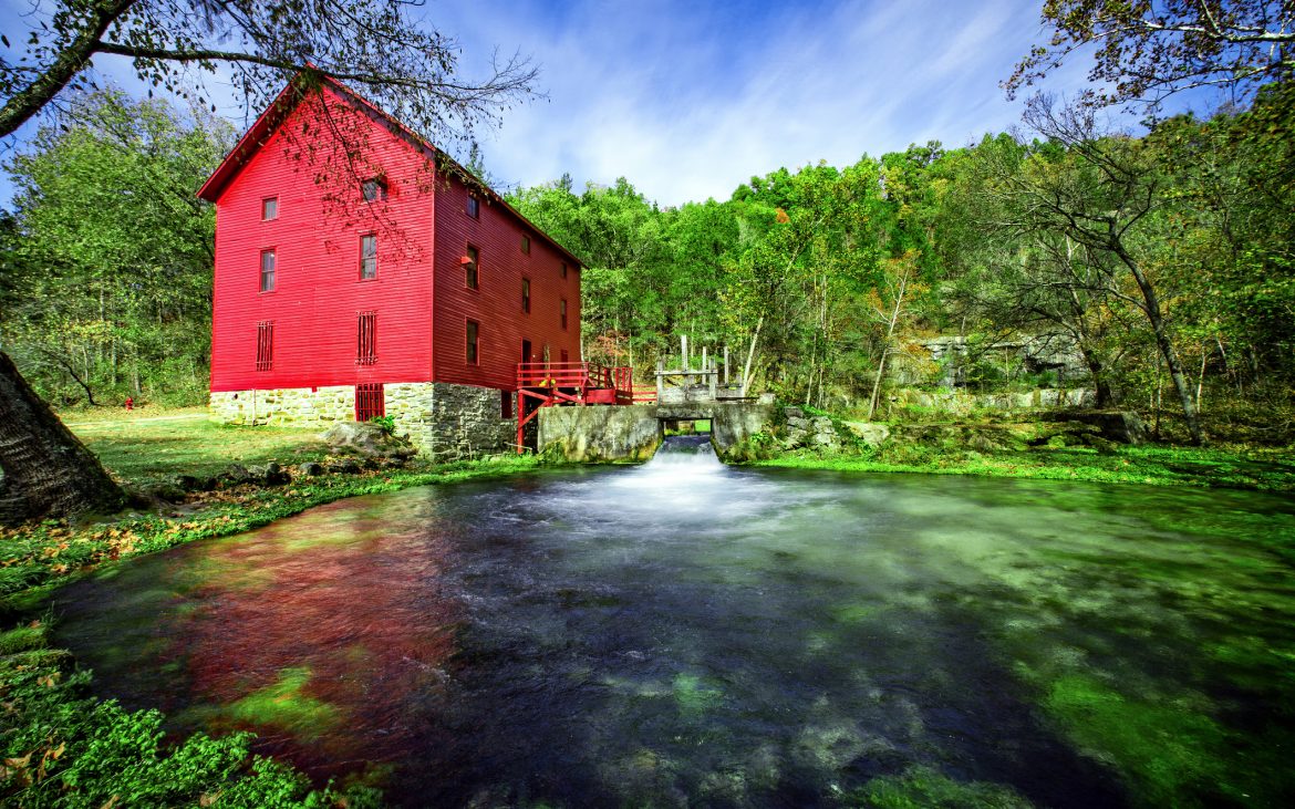 Ozark River running past a large red building.