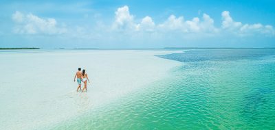Couple walking on a remote white-sand beach.