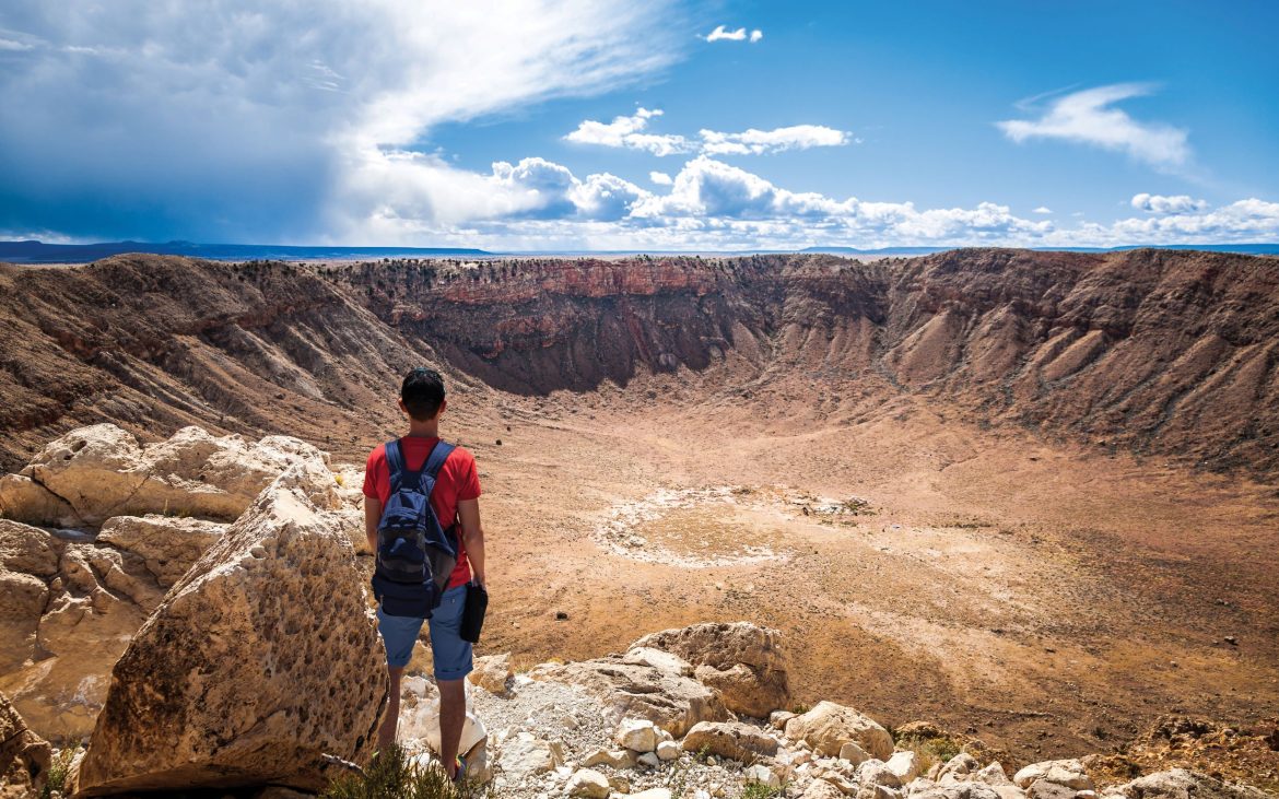 Hiker standing at the edge of large crater.