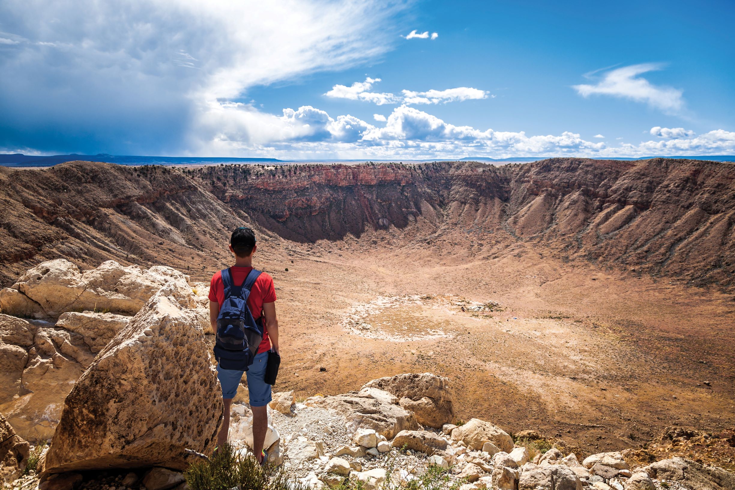 Hiker standing at the edge of large crater.