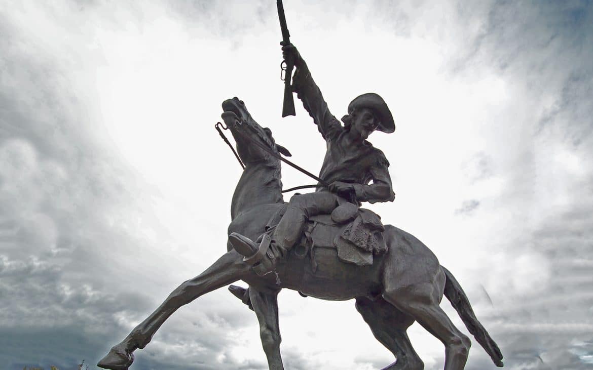 Statue of a cowboy on horseback raising his rifle high