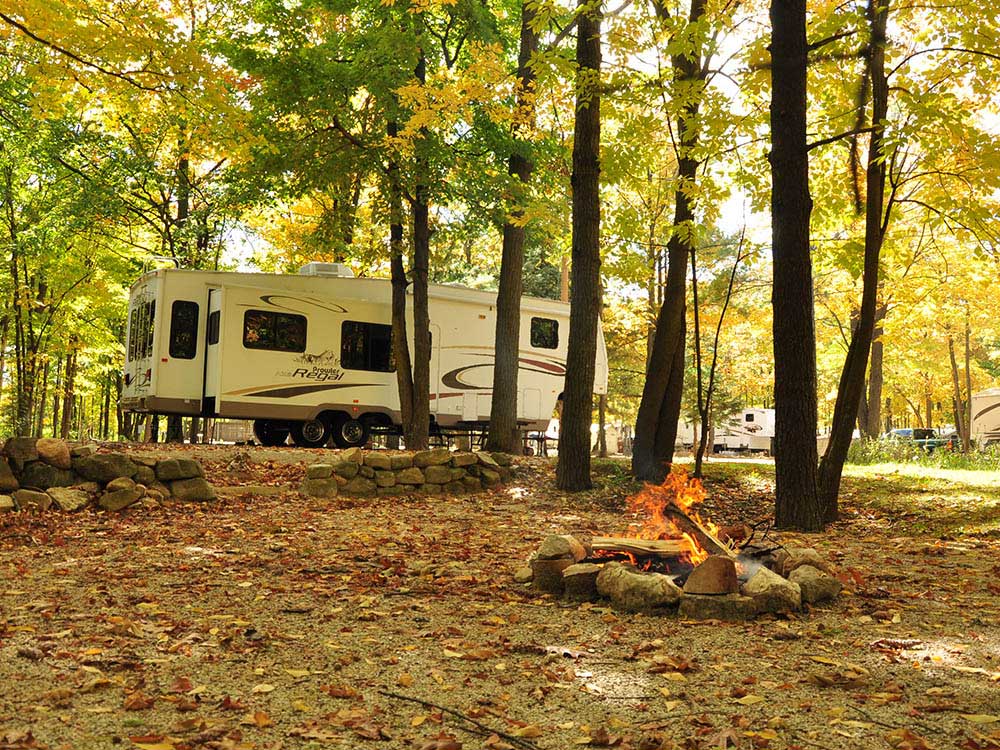 A fifth-wheel trailer parked in an autumn forest.