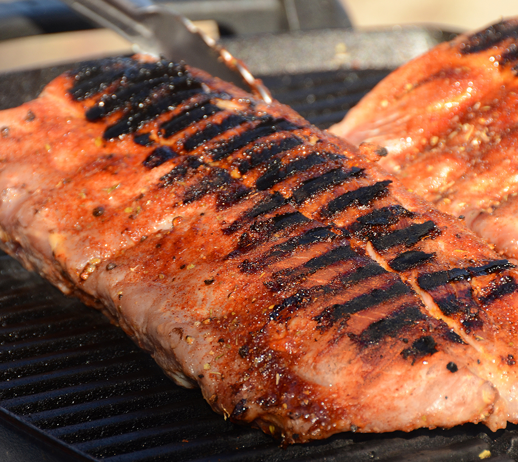 Big slab of ribs on a grill.