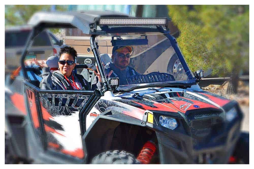 A couple drives an ATV through the desert.