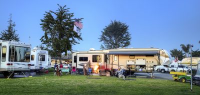 RV campers at Pismo Coast Village RV Resort with people in lawn chairs around firepit