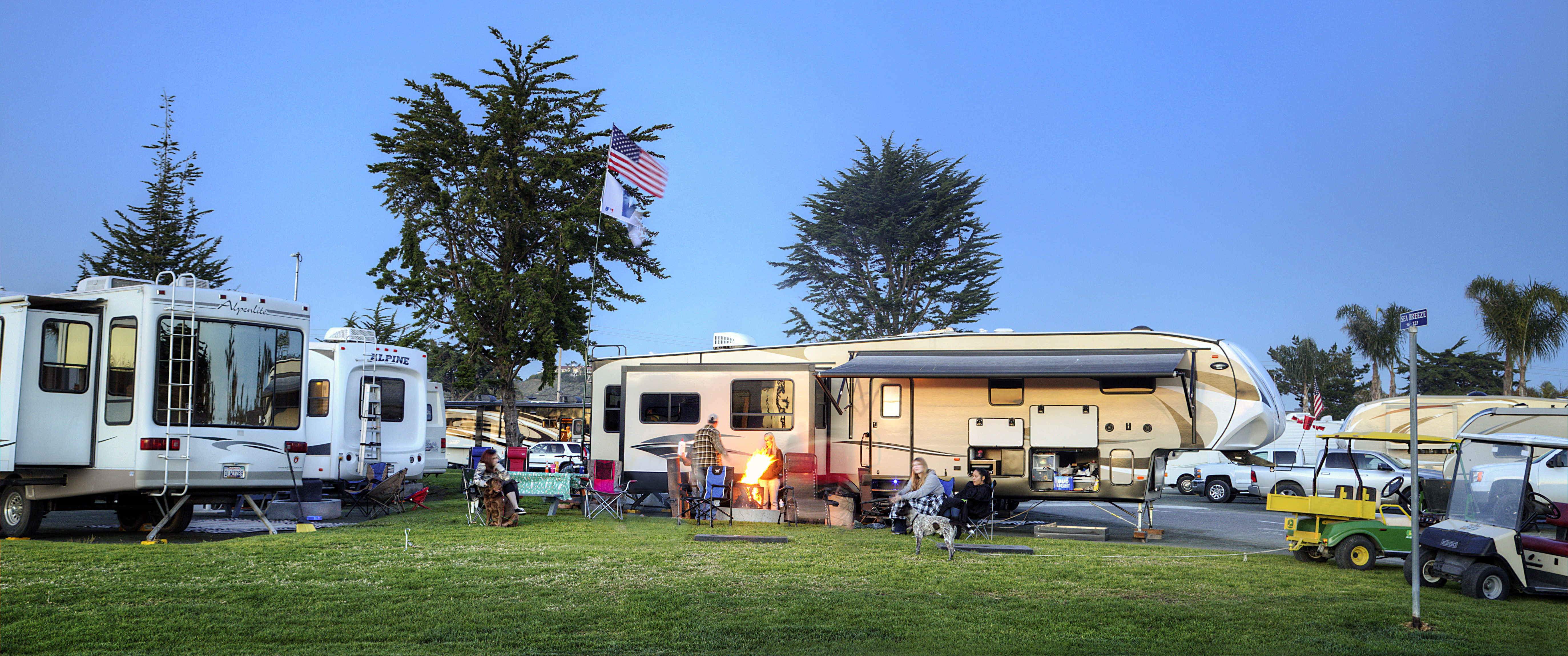 RV campers at Pismo Coast Village RV Resort with people in lawn chairs around firepit