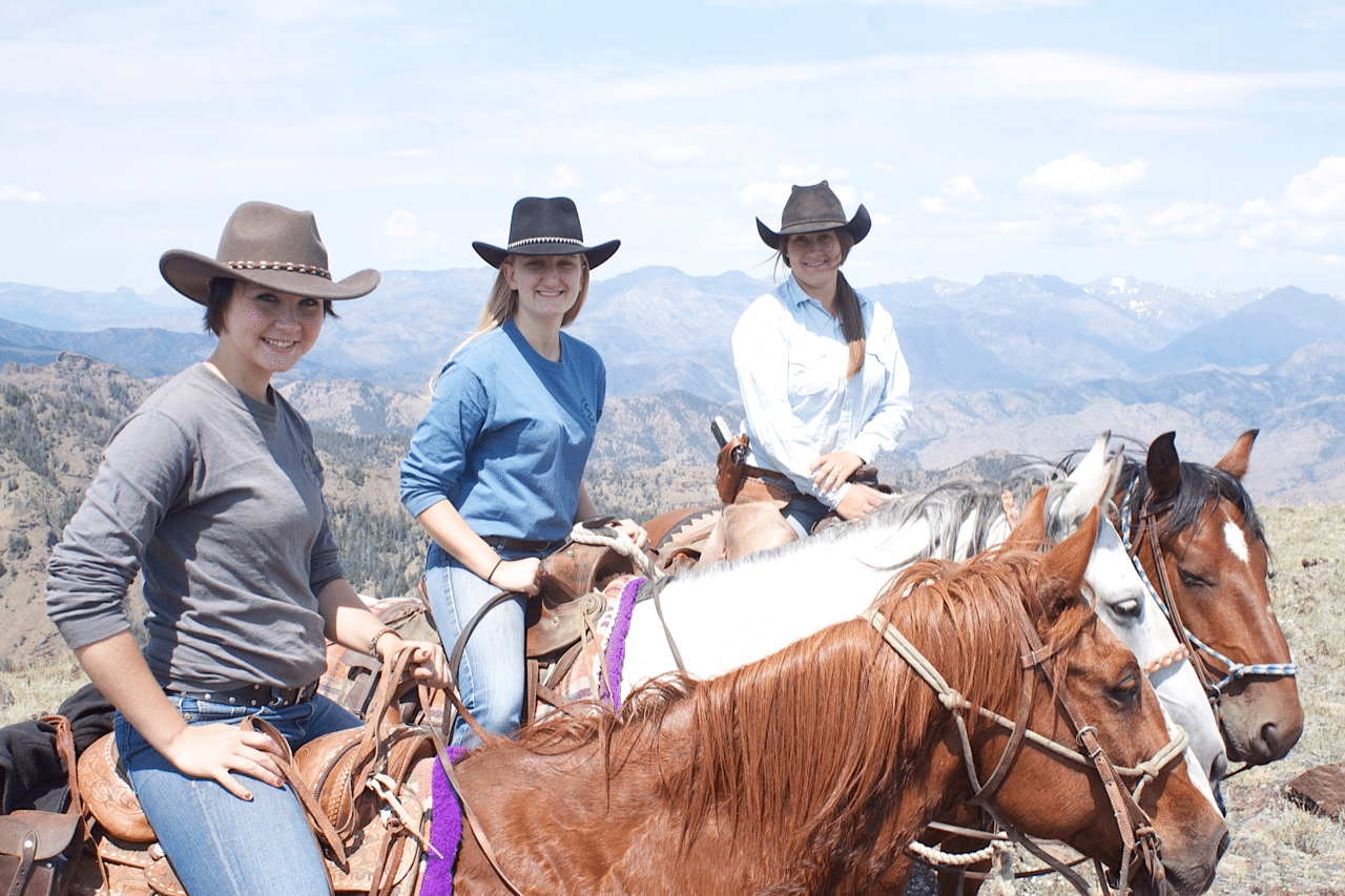 Three women on horseback against rugged mountains.