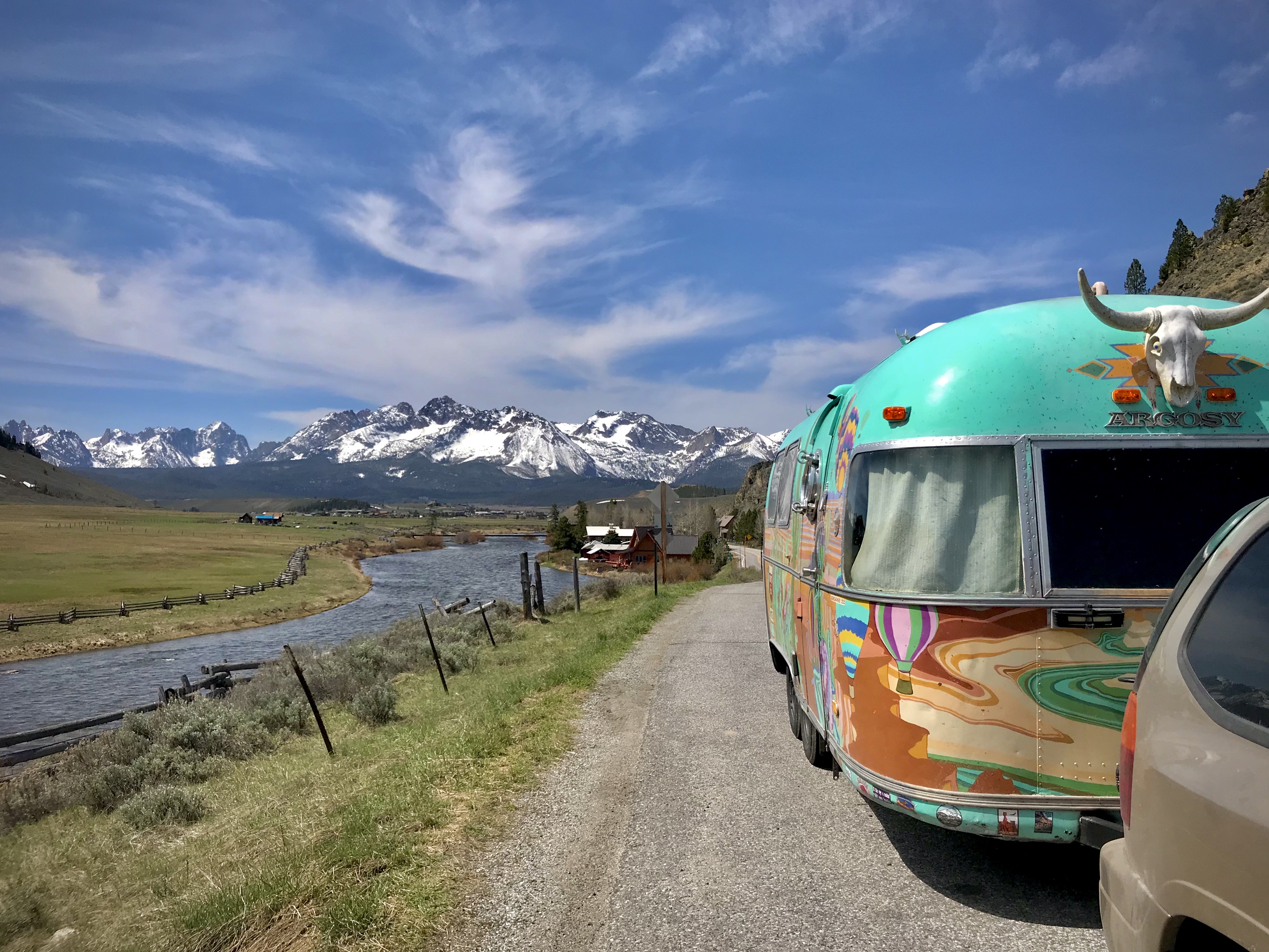 A colorful trailer on a road that runs parallel to a stream.