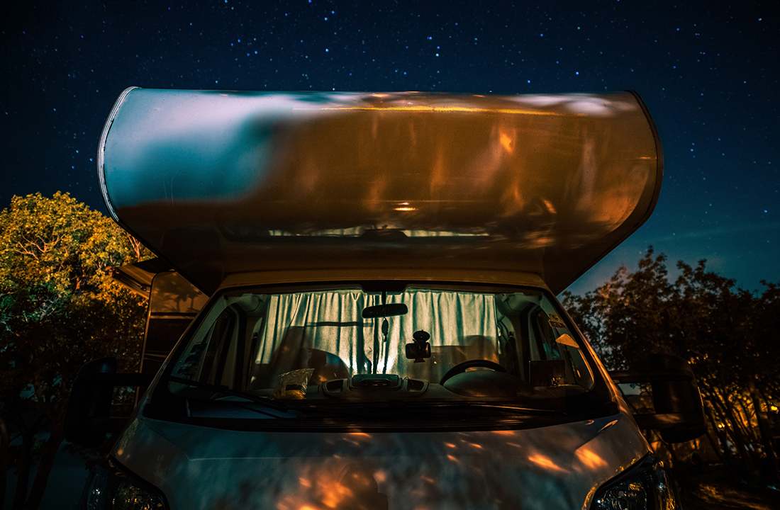 Night in RV Camper Van Motorhome Under Starry Sky. Motor Coach Front View. Road Travel Vistas Theme.