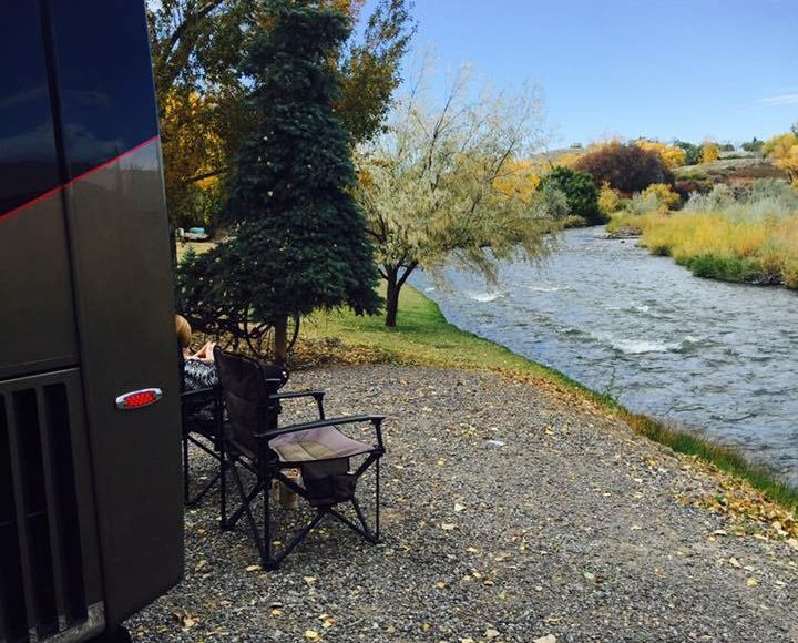 RV travelers relaxing on a waterfront campsite with motorhome.