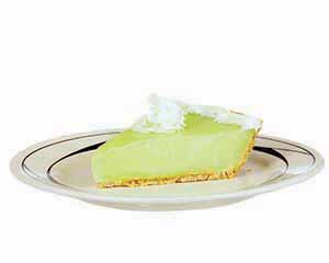 A plate with lime-green key lime pie topped with whipped cream.