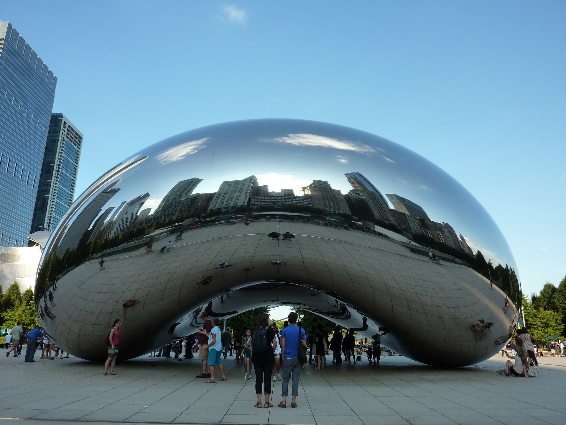Reflective bean sculpture surrounded by tourists.