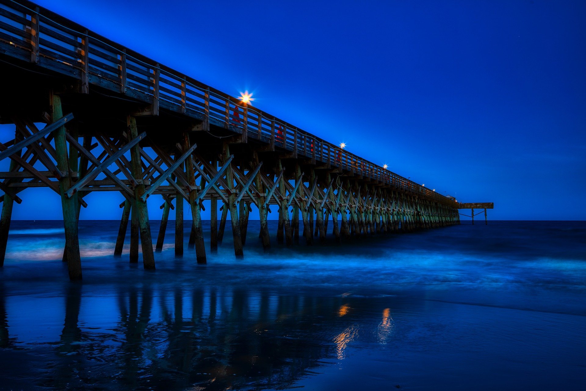 A pier stretches into the ocean at dusk.
