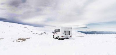 RV in snowfield under dark skies