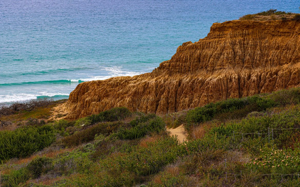 Beach Hikes in Southern California trail leads past a sandstone outcropping toward the sea.