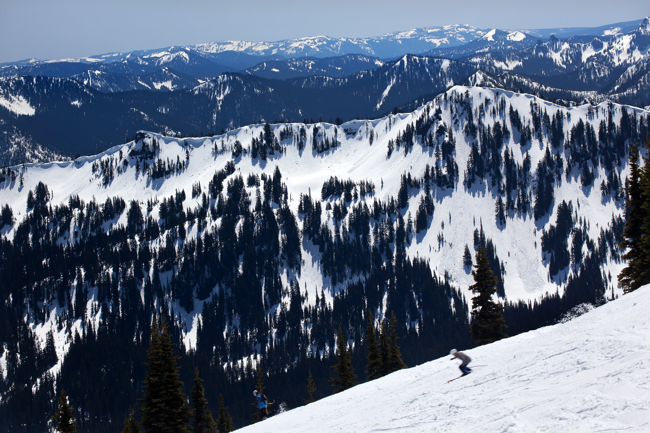Skiing a snowy ridge with mountains on the horizon