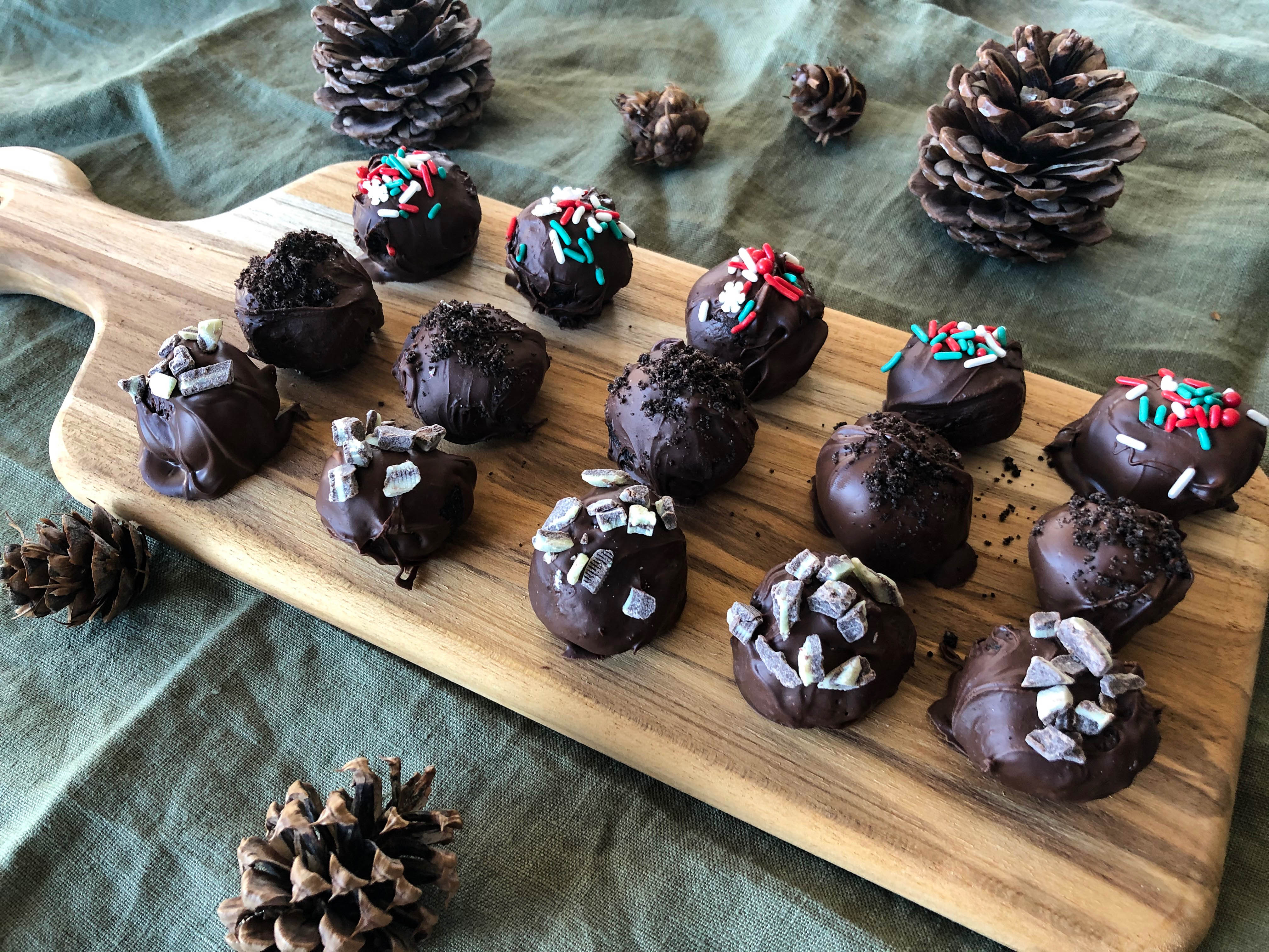 Chocolate truffles on a wooden sheet with pine cones.