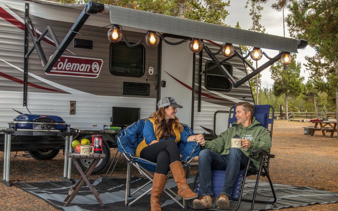 A couple in warm clothes lounge by their RV