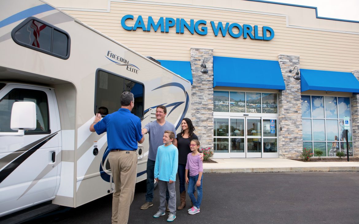 Buying a new or used RV A family smiles as they purchase a Class C motorhome