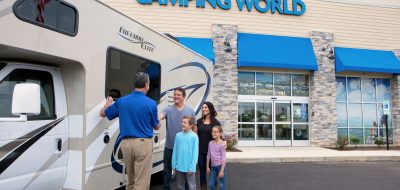 Buying a new or used RV A family smiles as they purchase a Class C motorhome